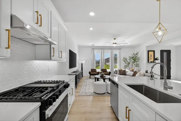 a large kitchen with stainless steel appliances granite countertop a sink a stove and a wooden floors