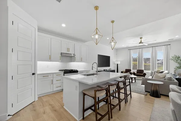 a open kitchen with stainless steel appliances granite countertop a sink a stove a dining table and chairs