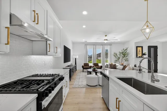 a large kitchen with stainless steel appliances granite countertop a sink a stove and a wooden floors