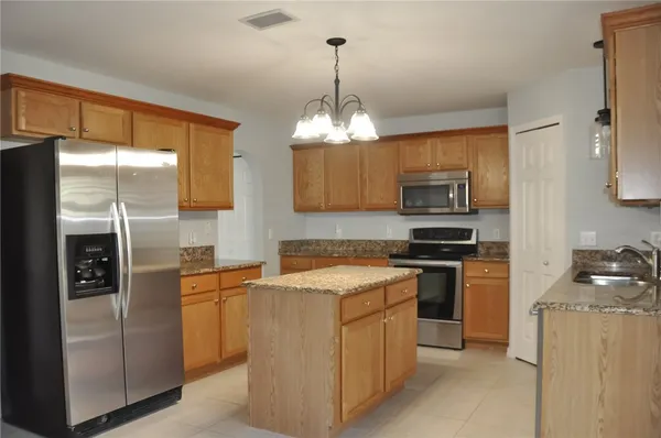a kitchen with stainless steel appliances granite countertop a refrigerator a stove top oven a sink and dishwasher