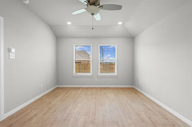 an empty room with wooden floor chandelier fan and windows