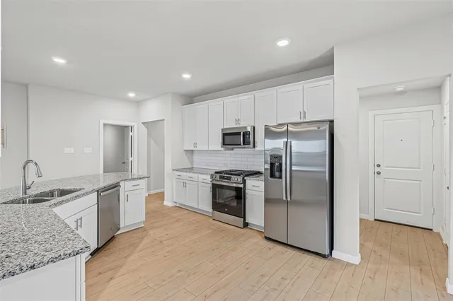 a kitchen with stainless steel appliances granite countertop a refrigerator a sink a stove and oven