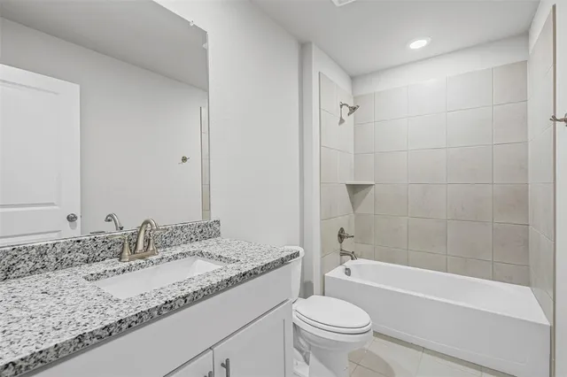 a bathroom with a granite countertop sink toilet mirror and bathtub