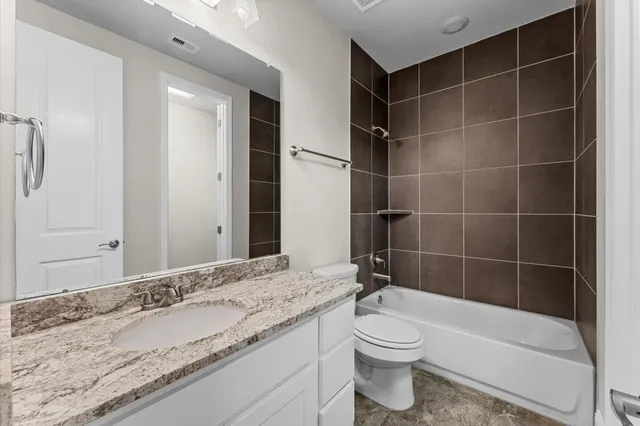 a bathroom with a granite countertop sink and a toilet