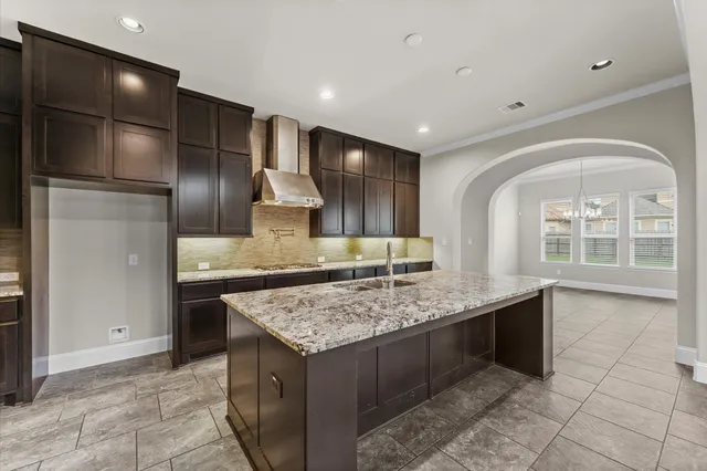 a kitchen with stainless steel appliances granite countertop a sink a stove and a wooden cabinets