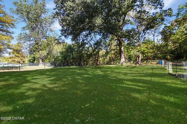 a view of grassy field with benches and trees all around