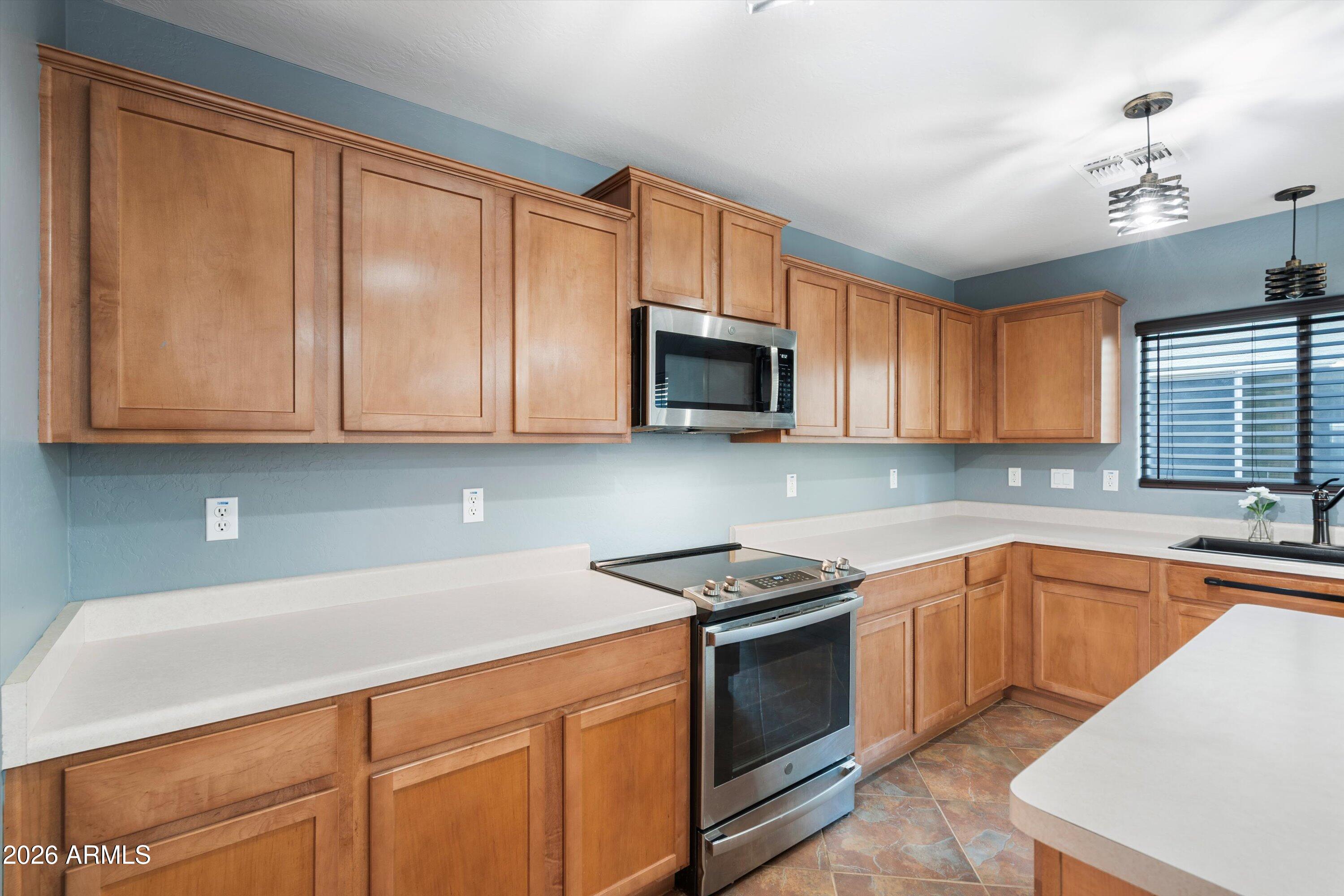 1231 West Ocotillo Street Coolidge, AZ 85128 - Photo 15 of 57 a kitchen with stainless steel appliances granite countertop wooden cabinets a stove top oven a sink and dishwasher