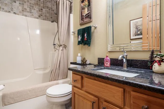 a bathroom with a granite countertop sink toilet and shower