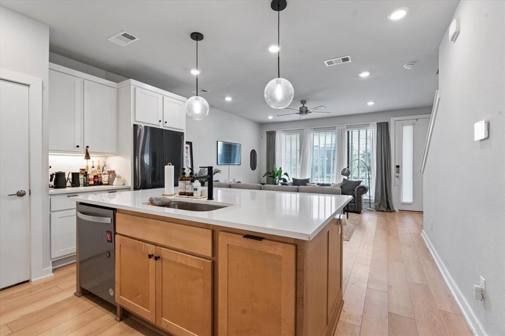2268 Rook Drive Dallas, TX 75211 - Photo 6 of 13 The kitchen features white cabinetry, a stainless steel refrigerator, and a kitchen island with a white countertop and a sink with a black faucet