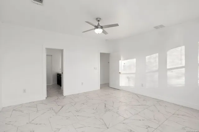 an empty room with windows and fan