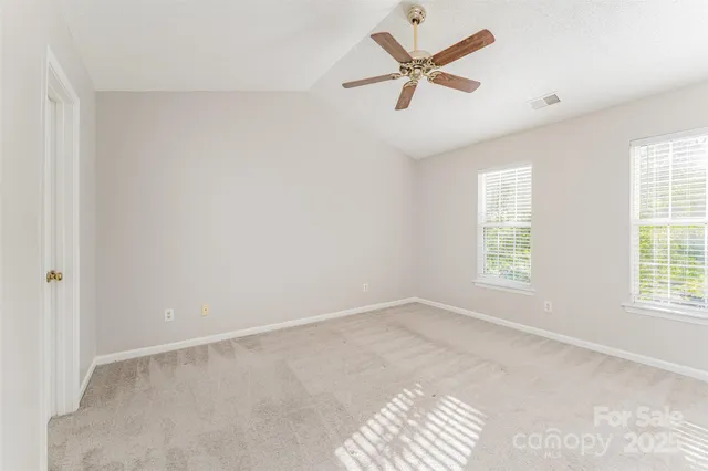 an empty room with windows and fan