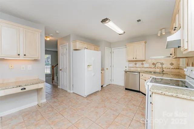 a kitchen with a refrigerator a stove top oven and white cabinets