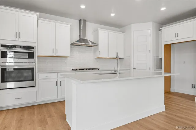 a large kitchen with stainless steel appliances granite countertop a lot of white cabinets and a stove