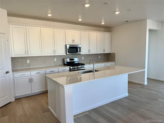 a large kitchen with stainless steel appliances granite countertop a stove a sink and white cabinets