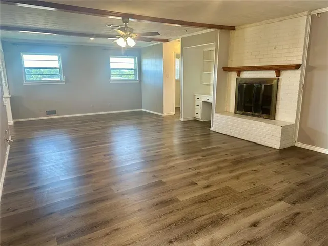 an empty room with wooden floor and fireplace