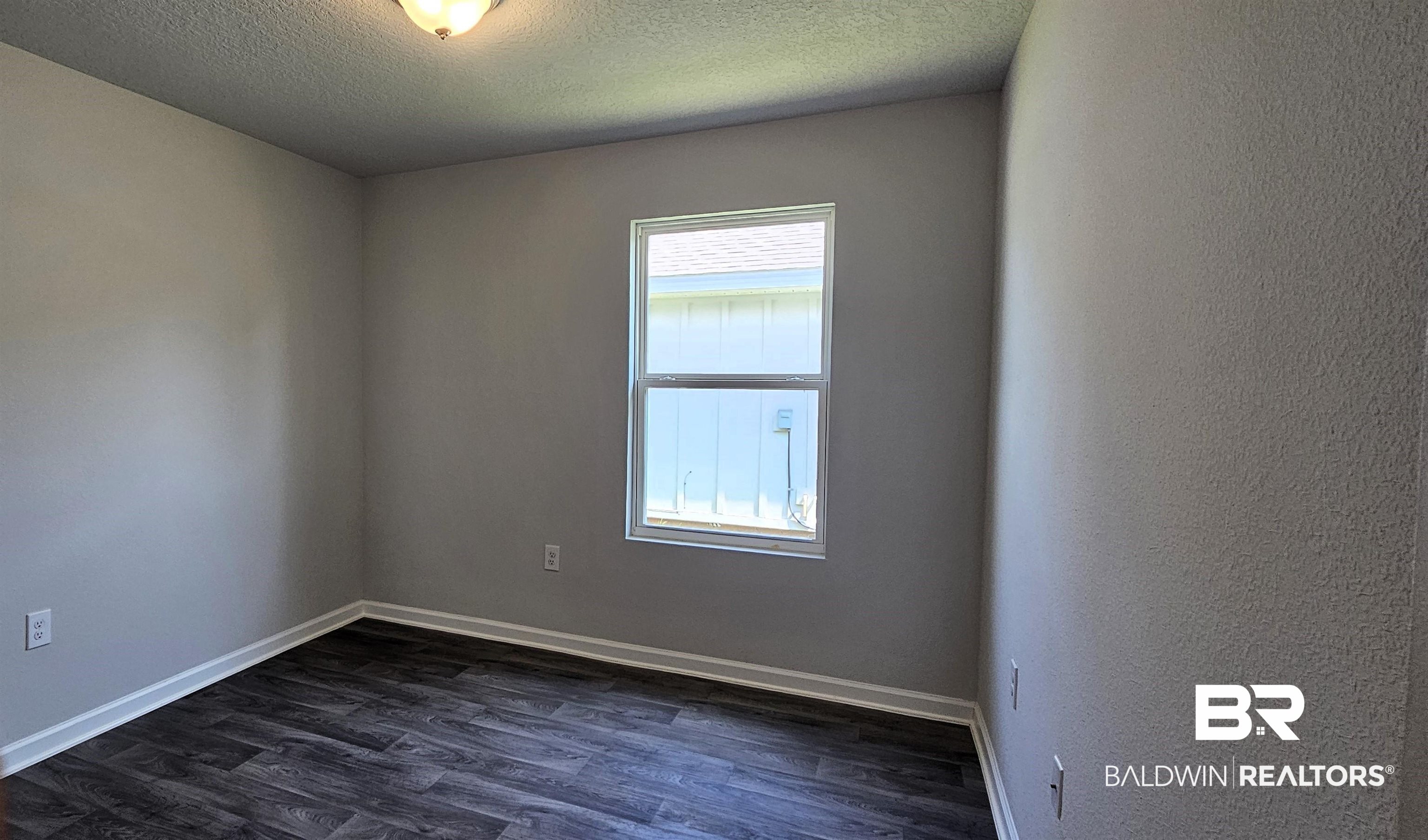1144 Sweet Laurel Street Foley, AL 36535 - Photo 4 of 10 Empty room featuring a textured ceiling, dark hardwood / wood-style flooring, and a healthy amount of sunlight