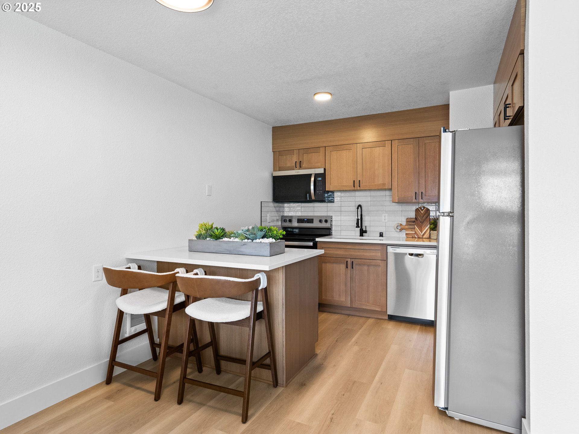 10701 Northeast 59th Street Vancouver, WA 98662 - Photo 9 of 16 a kitchen with a table chairs refrigerator and microwave