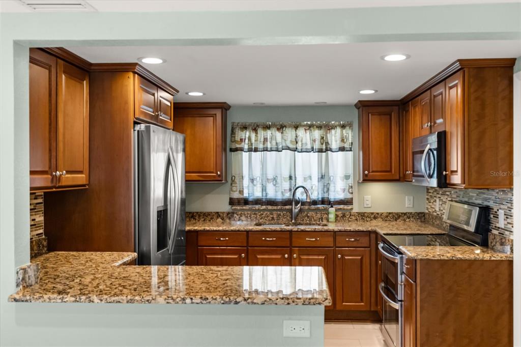 620 Jacaranda Street Dunedin, FL 34698 - Photo 7 of 30 a kitchen with stainless steel appliances granite countertop a refrigerator and a stove