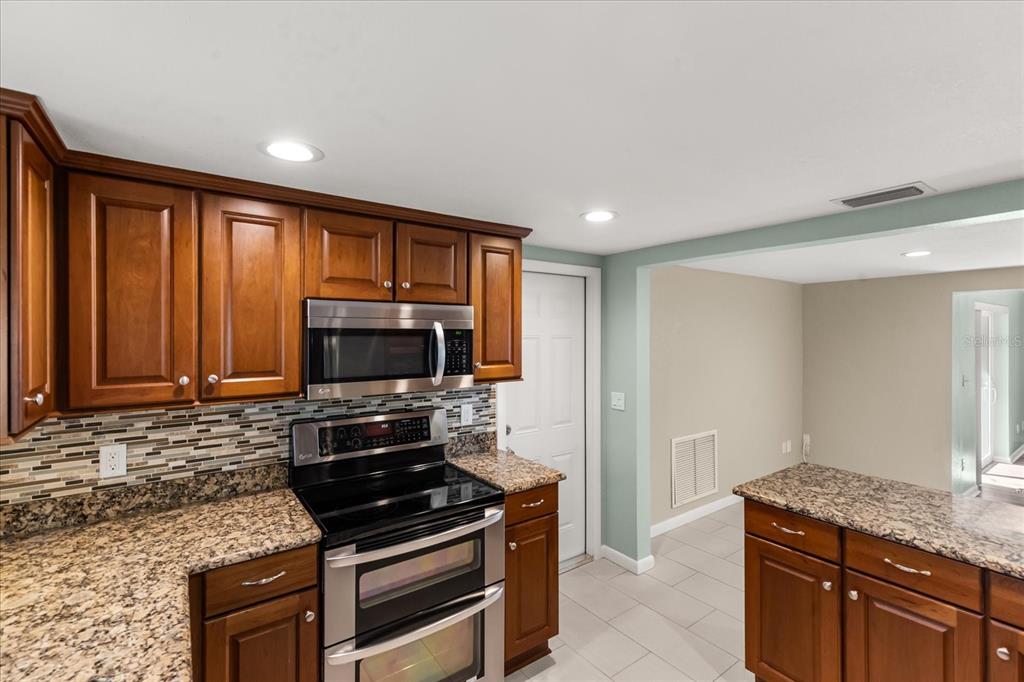 620 Jacaranda Street Dunedin, FL 34698 - Photo 9 of 30 a kitchen with granite countertop a stove and a microwave