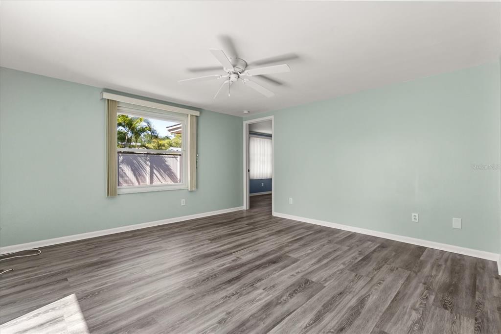 620 Jacaranda Street Dunedin, FL 34698 - Photo 10 of 30 an empty room with wooden floor ceiling fan and windows