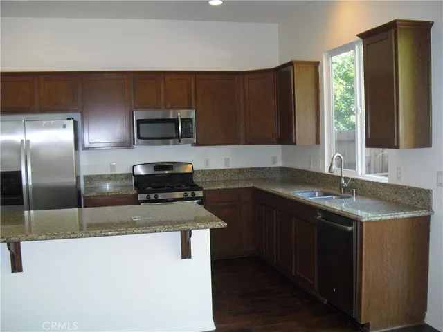 a kitchen with granite countertop a refrigerator and a sink