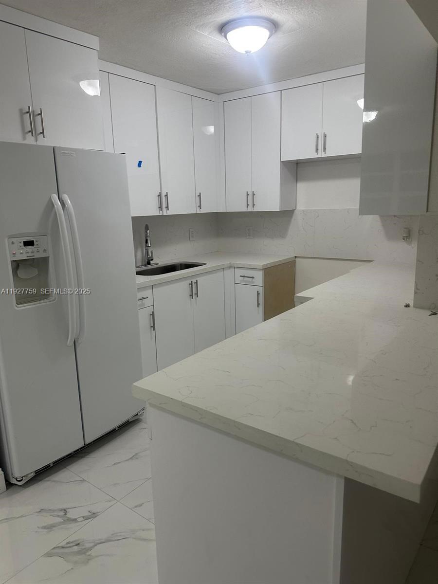 6750 Allen Street Hollywood, FL 33024 - Photo 32 of 79 a kitchen with stainless steel appliances a refrigerator sink and white cabinets