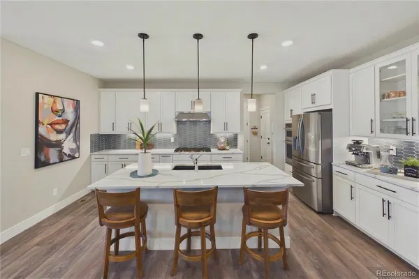 a kitchen with stainless steel appliances kitchen island granite countertop a dining table chairs and white cabinets