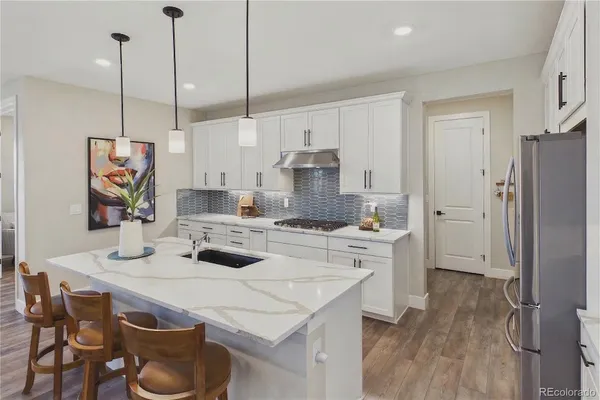 a kitchen with stainless steel appliances a stove a sink a refrigerator a center island a table and chairs