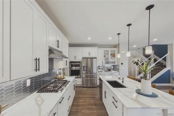 a large kitchen with stainless steel appliances kitchen island granite countertop a sink a stove and a wooden floors