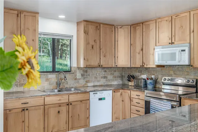 a kitchen with stainless steel appliances granite countertop white cabinets sink and large window