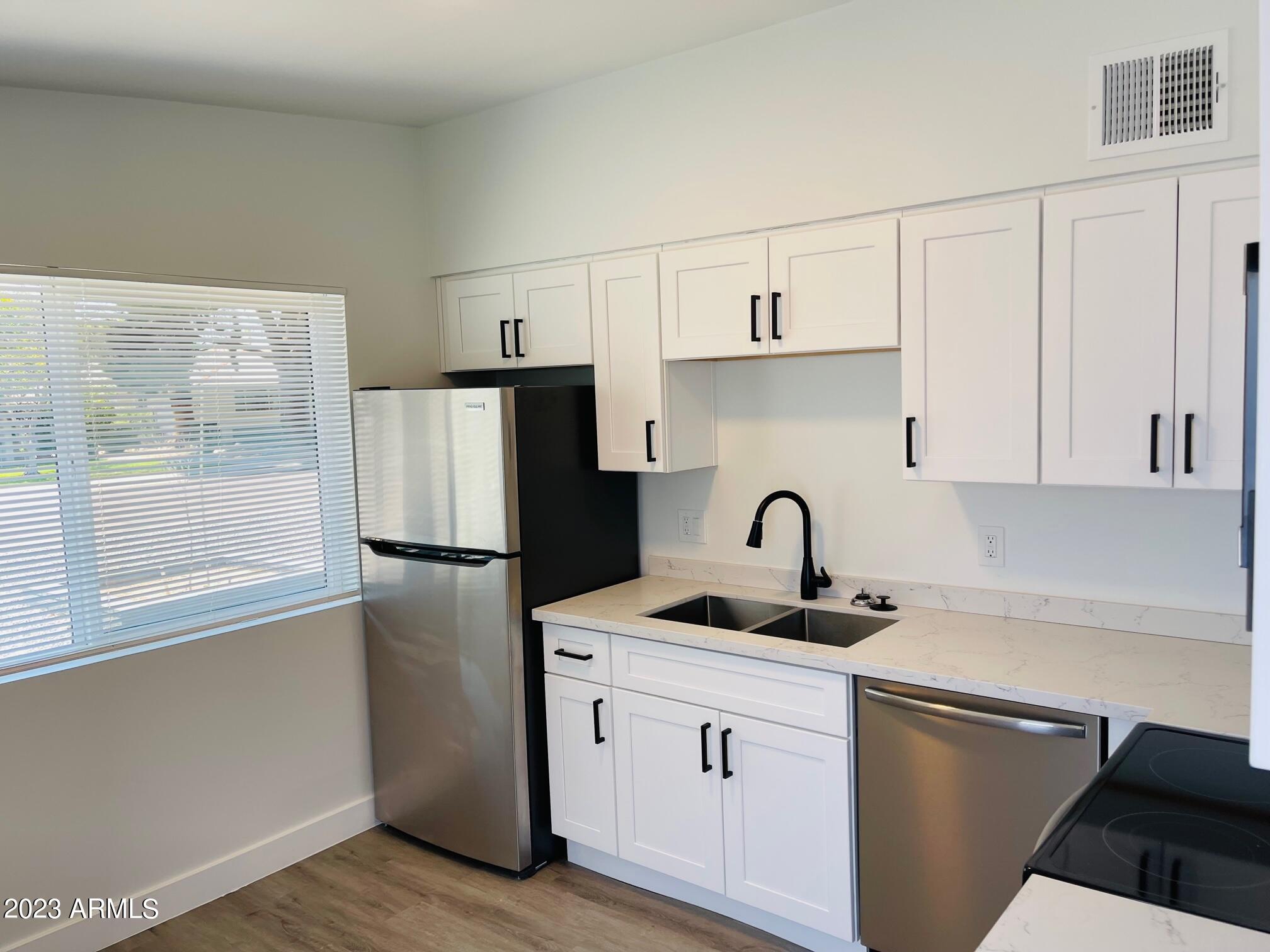 6233 North 13th Place, Unit 1 Phoenix, AZ 85014 - Photo 8 of 20 a kitchen with stainless steel appliances granite countertop a refrigerator sink and white cabinets