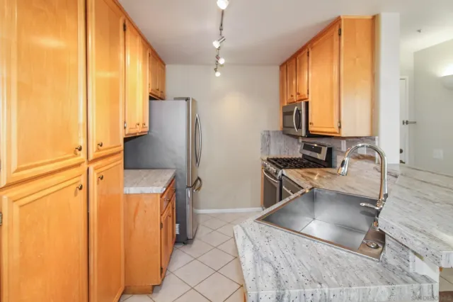 a kitchen with stainless steel appliances granite countertop a refrigerator a stove and a sink with wooden floor