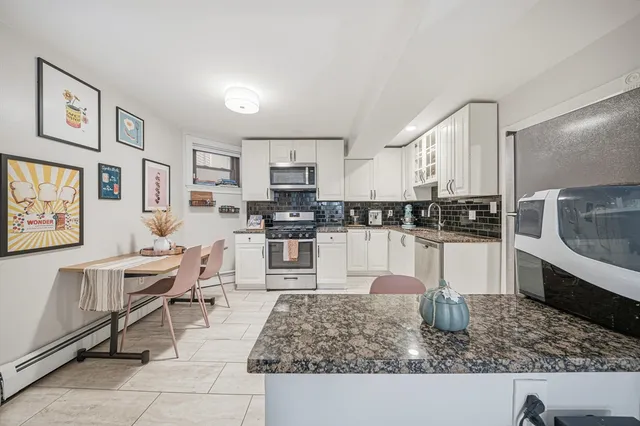 a kitchen with granite countertop a stove a sink and white cabinets