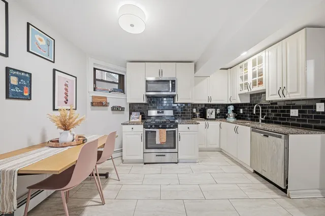 a kitchen with stainless steel appliances granite countertop a stove top oven a sink a dining table and chairs