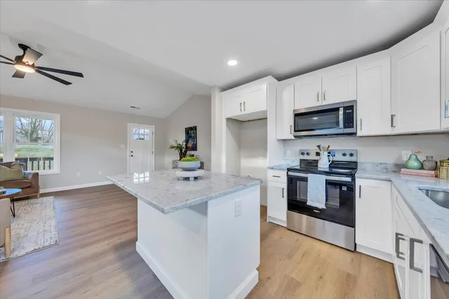 a kitchen with stainless steel appliances granite countertop a stove top oven a sink dishwasher and a refrigerator with wooden floor