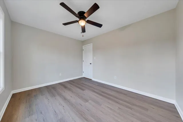 an empty room with wooden floor and ceiling fan