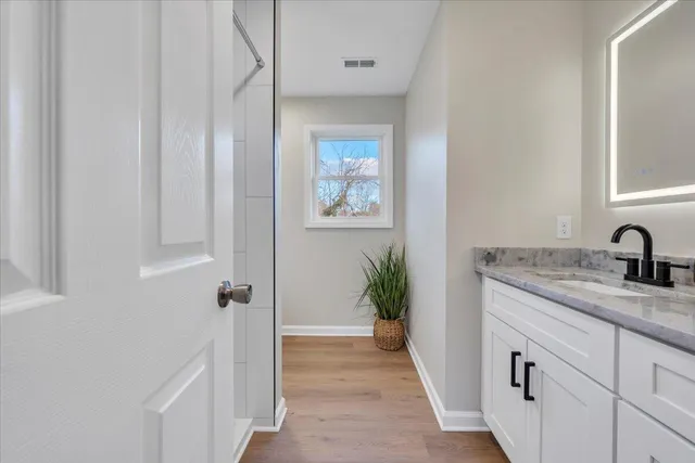 a bathroom with a granite countertop sink a mirror and shower