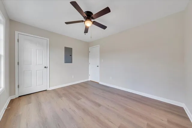 an empty room with wooden floor and ceiling fan