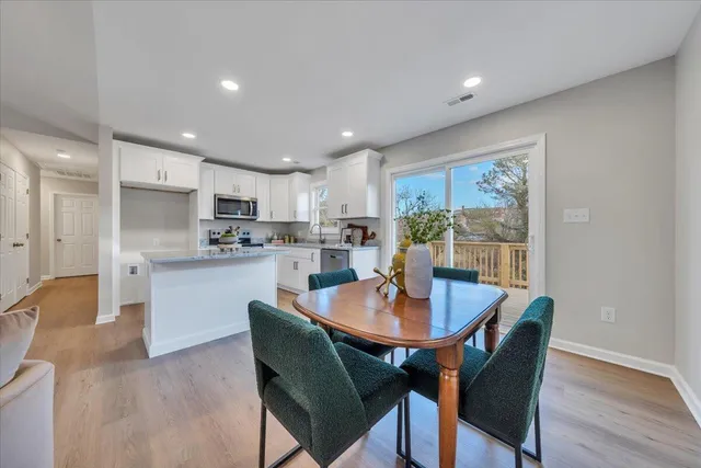 a open dining room with stainless steel appliances a table and chairs