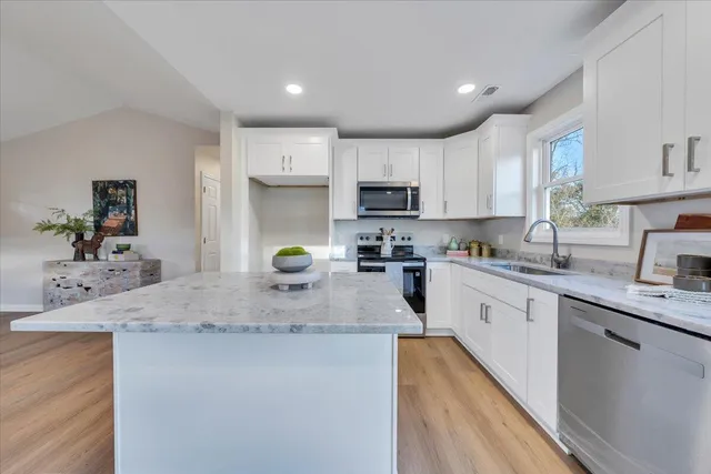 a kitchen with kitchen island granite countertop a sink appliances cabinets and a counter top space