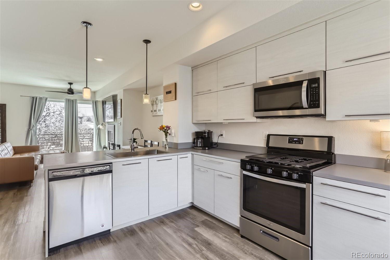 a kitchen with stainless steel appliances white cabinets granite counter tops and a view of living room