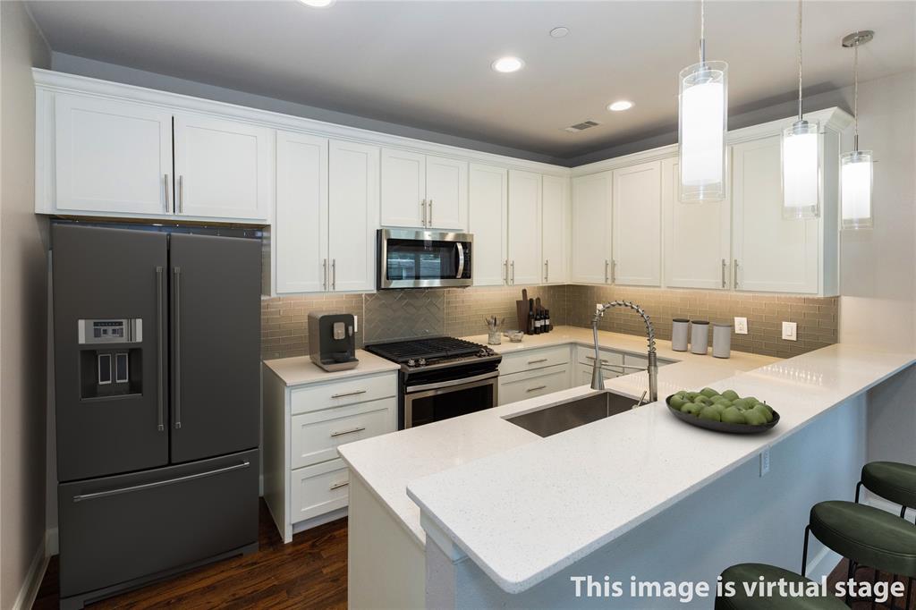 2016 North Fitzhugh Avenue, Unit 101 Dallas, TX 75204 - Photo 8 of 26 Kitchen with appliances with stainless steel finishes, white cabinetry, a peninsula, backsplash, and hanging light fixtures