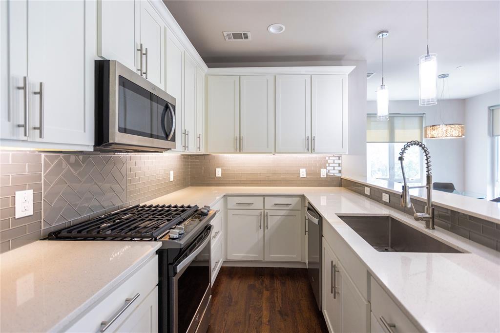 2016 North Fitzhugh Avenue, Unit 101 Dallas, TX 75204 - Photo 10 of 26 Kitchen featuring stainless steel appliances, decorative light fixtures, white cabinets, light stone counters, and dark wood-style floors