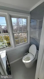 a bathroom with a toilet a sink a window and mirror