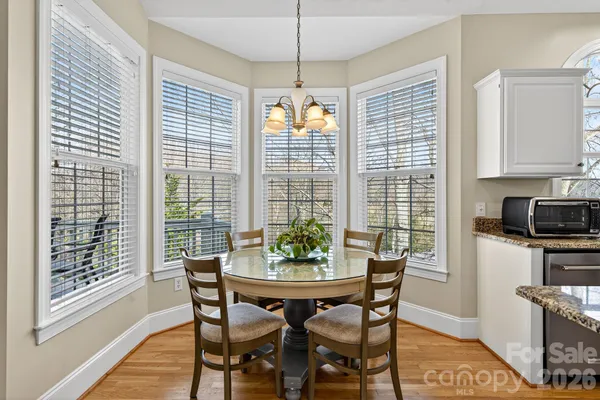 a kitchen with stainless steel appliances granite countertop a refrigerator a stove top oven a sink dishwasher and white cabinets with wooden floor