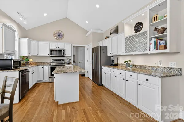 a kitchen with granite countertop white cabinets stainless steel appliances and a window