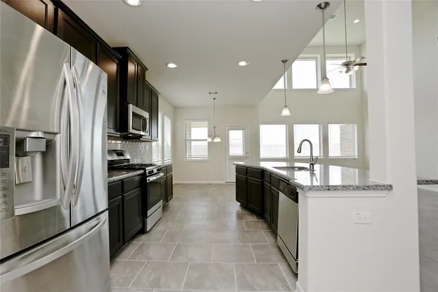 a large kitchen with granite countertop lots of counter top space a sink and stainless steel appliances