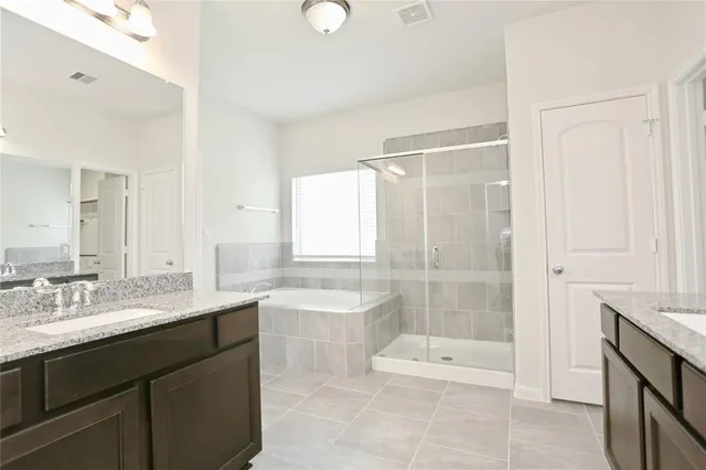 a bathroom with a double vanity sink large mirror and a bathtub