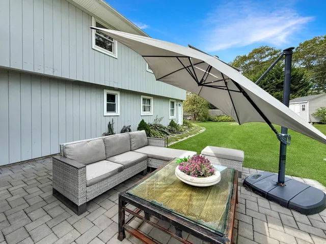 a view of a patio with couches table and chairs under an umbrella