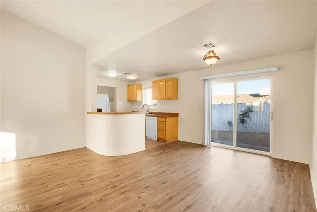 a view of a kitchen an empty room and wooden floor